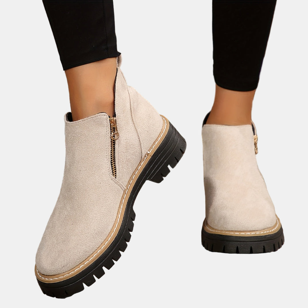 Beige suede ankle boots with side zipper and tan stitching, chunky lug sole.