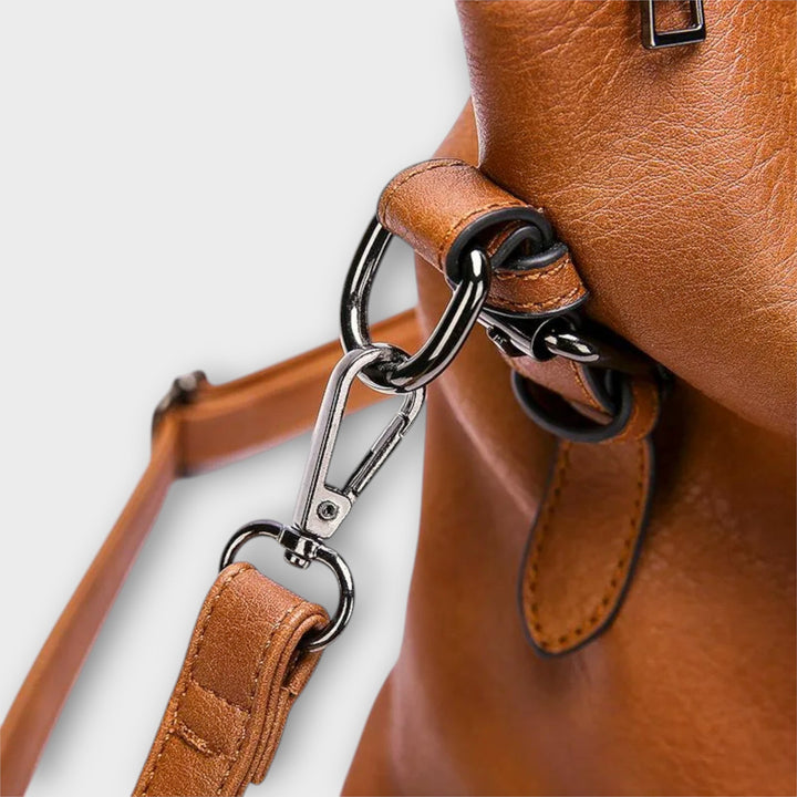 Brown shoulder bag close-up: metal ring connector and leather strap with buckle