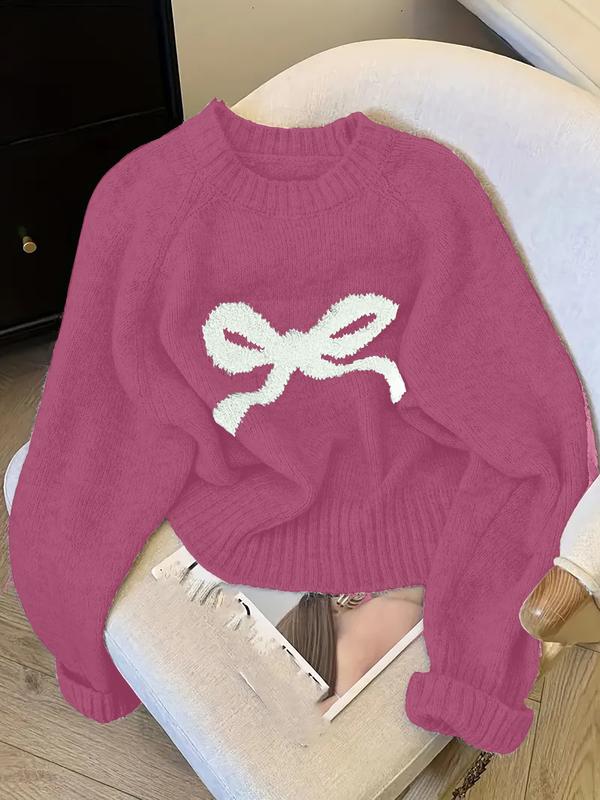 Pink knit sweater with ribbed crew neck, cuffs, and white bow intarsia