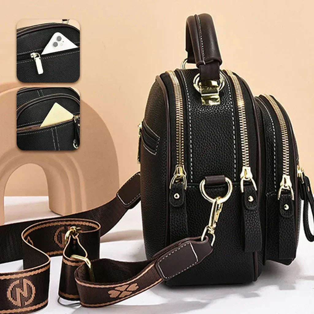 Black mini crossbody shoulder bag with gold-tone hardware, front zip pocket, and strap
