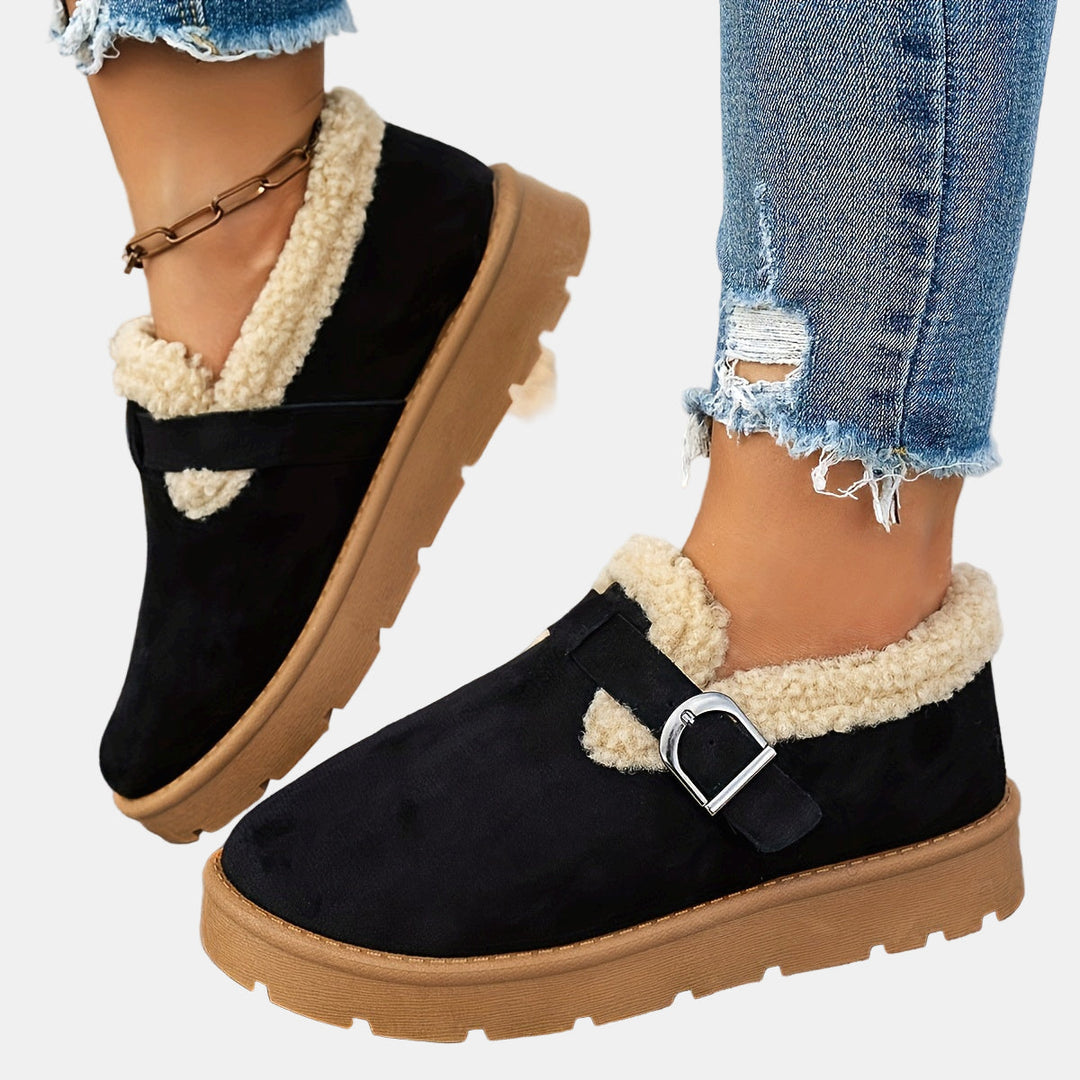 Black fleece-lined ankle boots with side strap and buckled metal detail, rugged sole