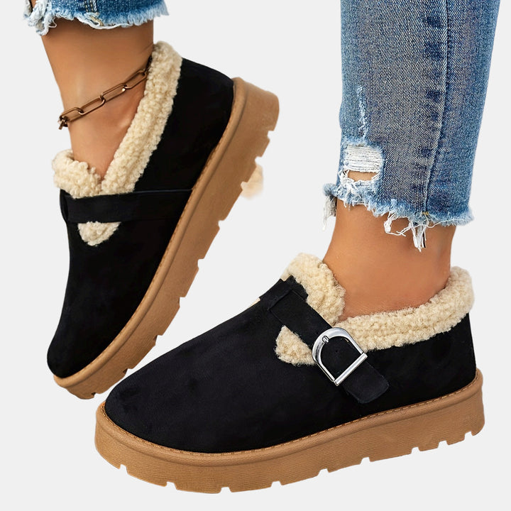 Black fleece-lined ankle boots with side strap and buckled metal detail, rugged sole