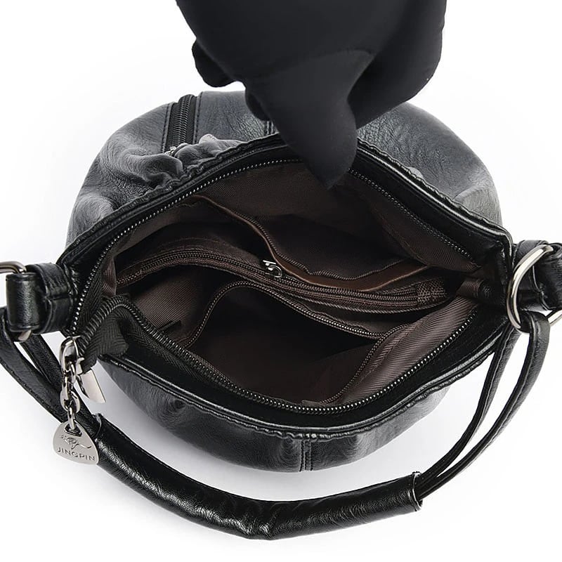 Black handbag interior view with main zipper opening and stitched inner compartments