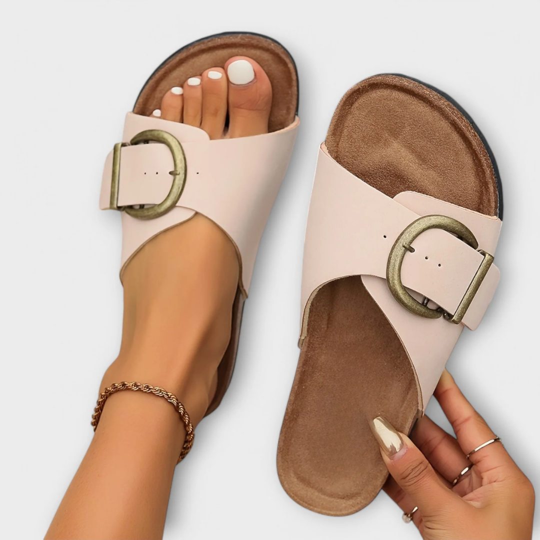 Orthopedic sandals in cream with adjustable ankle strap and round buckle over cork footbed.