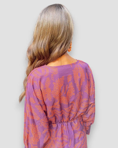 Purple V-neck wrap dress, long sleeves, and button-tie back with ornate leaf print.