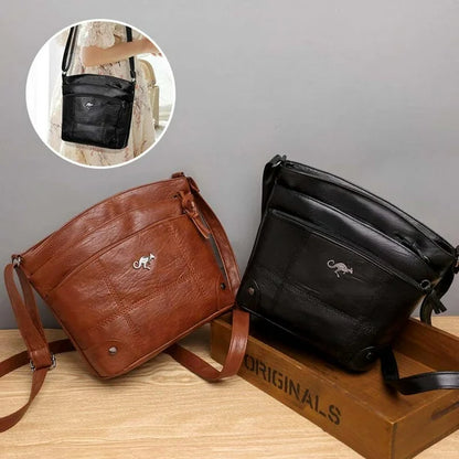 Two leather crossbody bags, brown and black, with kangaroo logos and zip tops.