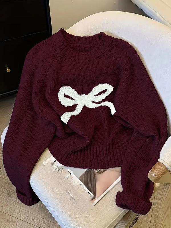 Burgundy knit sweater with ribbed crew neck, cuffs, and white bow intarsia