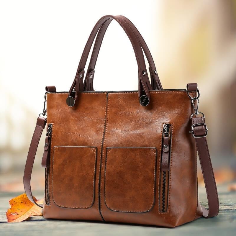 Brown PU leather crossbody tote with front pockets, metal rings, and attached shoulder strap.