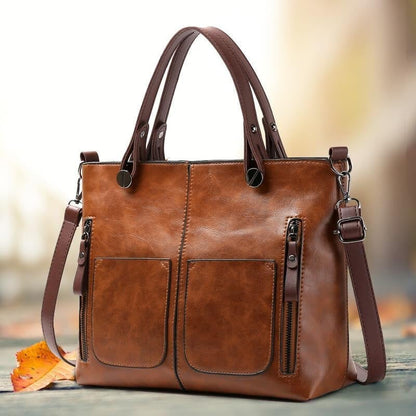 Brown PU leather crossbody tote with front pockets, metal rings, and attached shoulder strap.