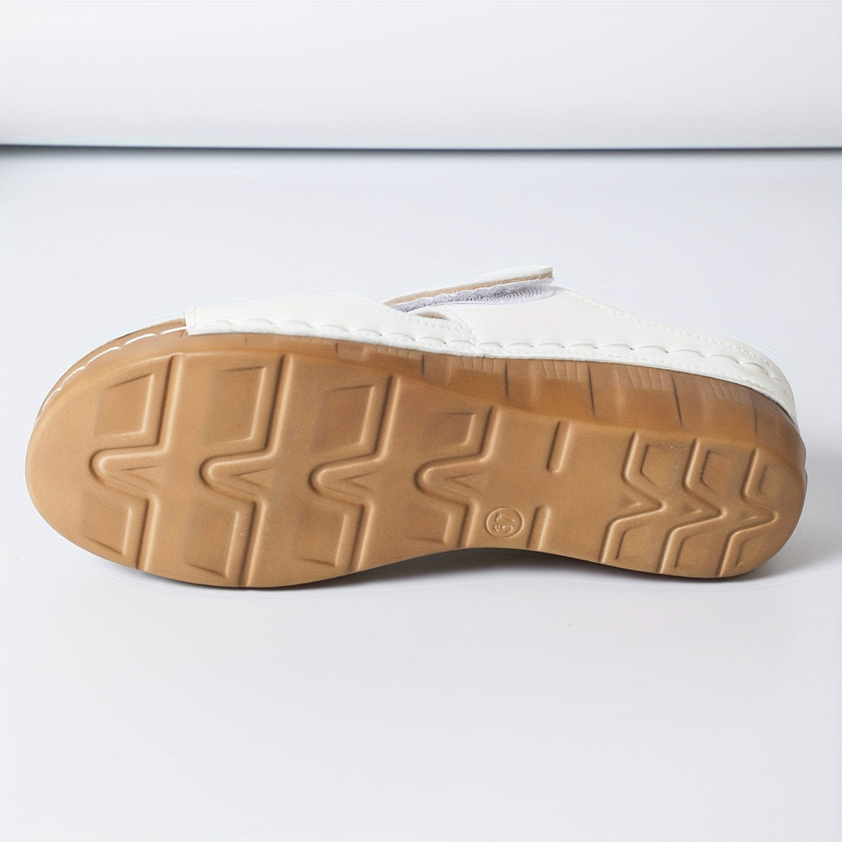 White sandal outsole with textured traction pattern and molded ridges