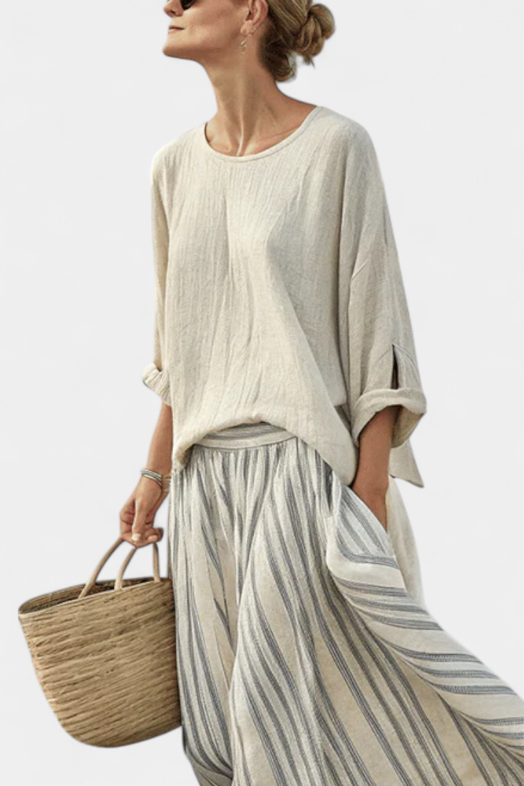 Cream blouse with round neckline worn with a gray-and-white striped midi skirt