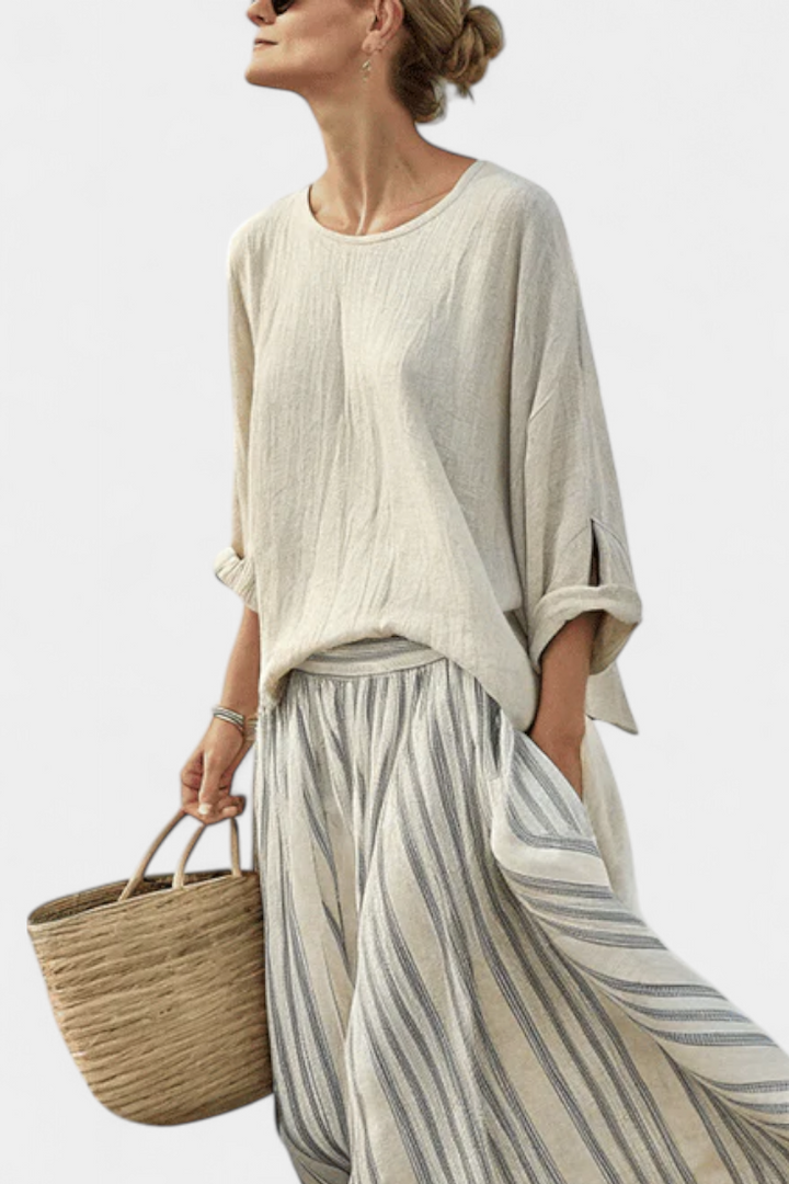 Cream blouse with round neckline worn with a gray-and-white striped midi skirt