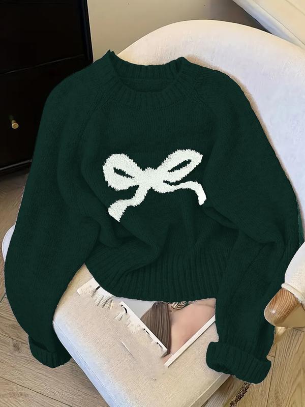 Green knit sweater with ribbed crew neck, cuffs, and white bow intarsia