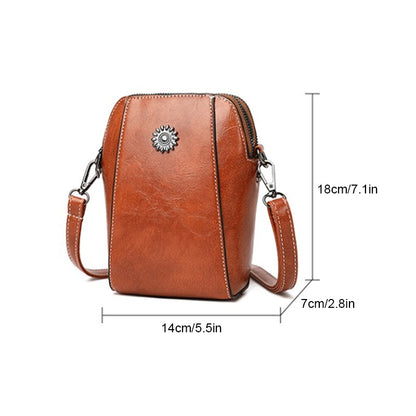 Brown compact mini handbag with crossbody strap, zipper top, and decorative sunburst emblem.