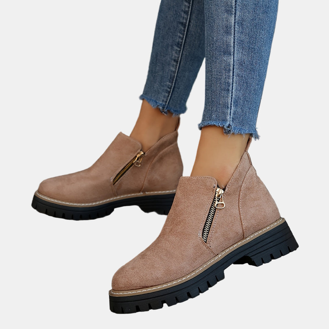 Tan suede ankle boots with side zipper, tan-stitched welt, and black lug sole.