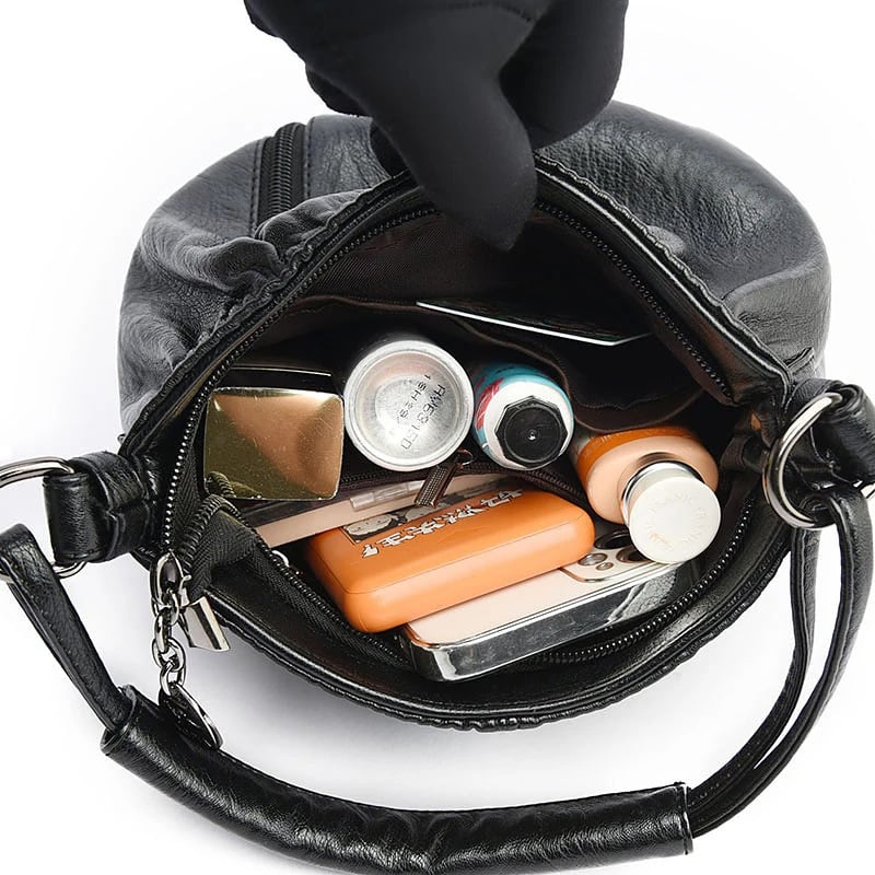 Black handbag interior filled with small items, showing zip opening and inner pockets