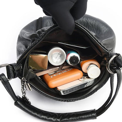 Black handbag interior filled with small items, showing zip opening and inner pockets