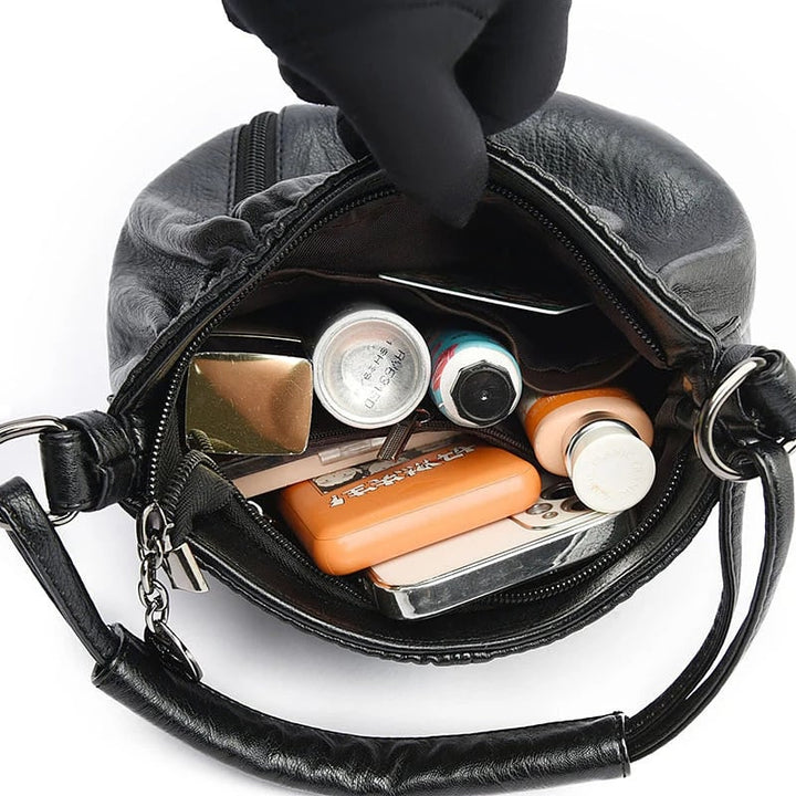 Black handbag interior filled with small items, showing zip opening and inner pockets