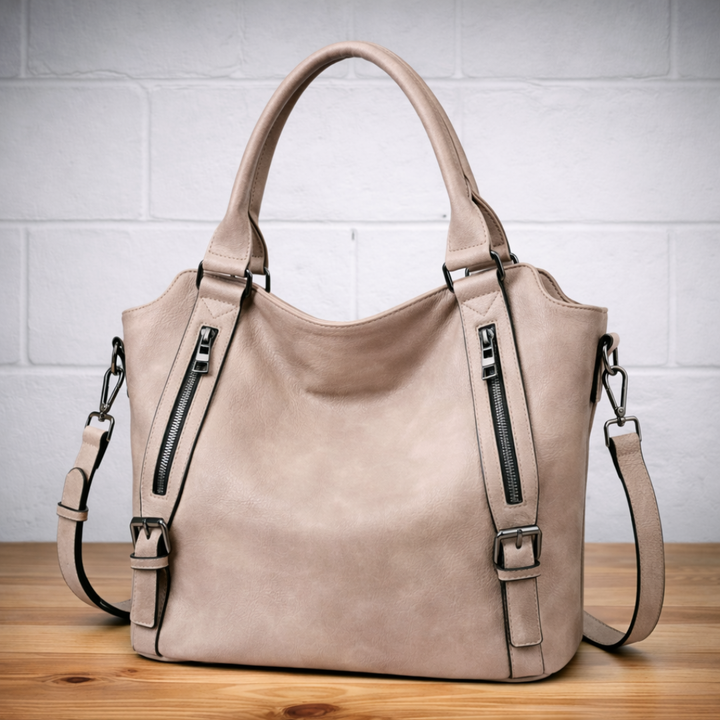 Beige leather hobo tote bag with two top handles, two zip pockets, and crossbody strap