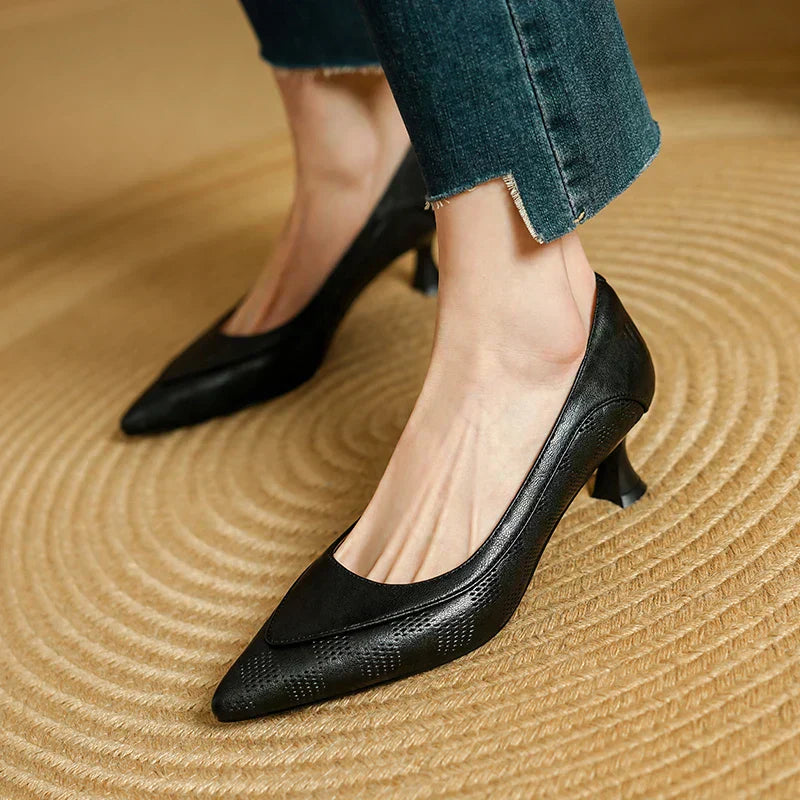 Black low block heel pumps with pointed toe and smooth curved vamp.
