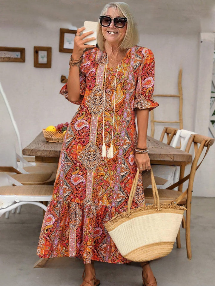 Boho grace dress in orange-red paisley print with tassel-trimmed neckline and flared tiered skirt