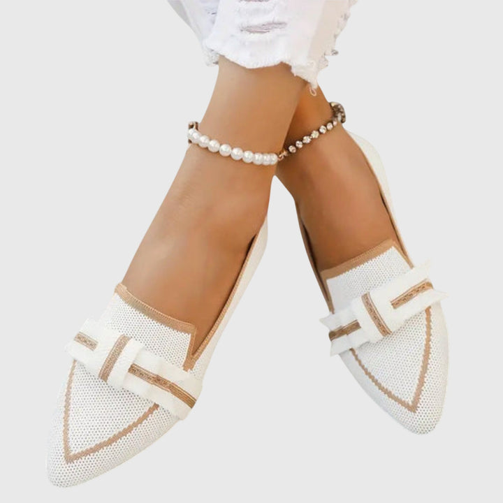 White slip-on comfy shoes with tan accents and side bow detail