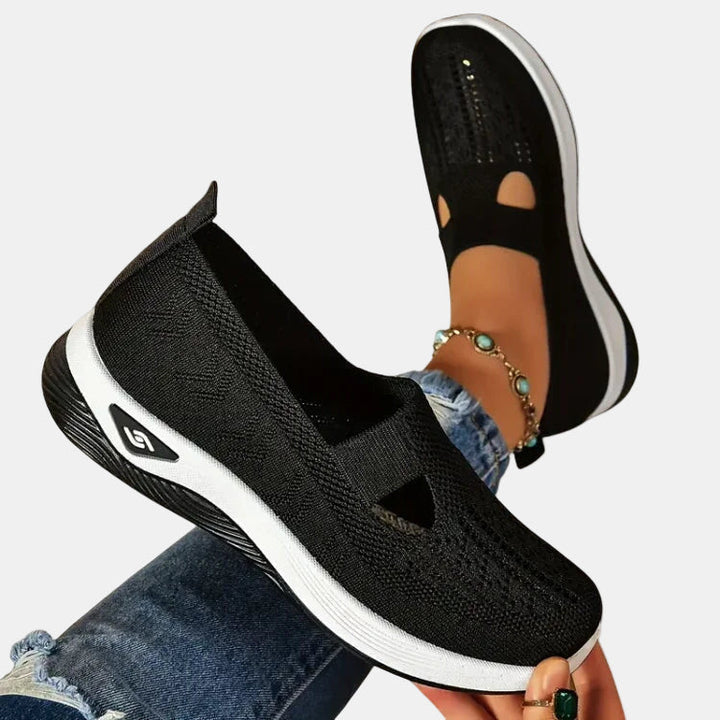 Black slip-on orthopedic walking shoe, knit upper with open toe cutouts, white sole.