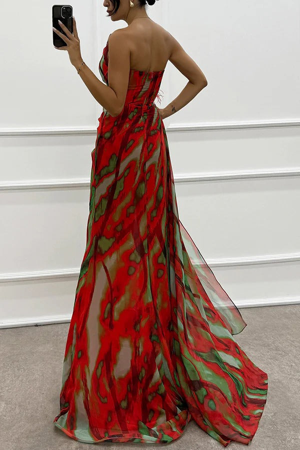 Back view of red strapless maxi dress with abstract green and blue print, feathered detail