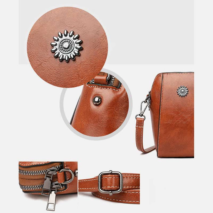 Brown mini handbag detail view: zipper pull, crossbody strap, and sunburst emblem.