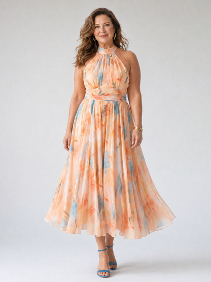 Soft halter midi dress with peach-and-blue watercolor print, fitted waist, flowing midi skirt