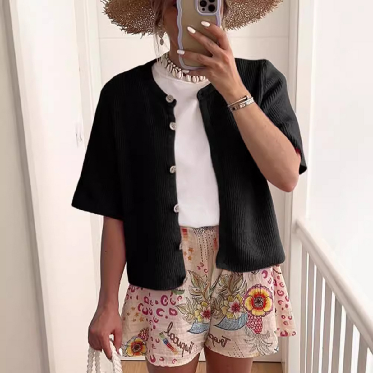 Black short-sleeve button-front knit cardigan with ribbed texture and rounded collar.