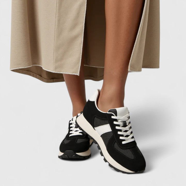 Black lace-up sneakers with white stripe panels and chunky white rubber sole
