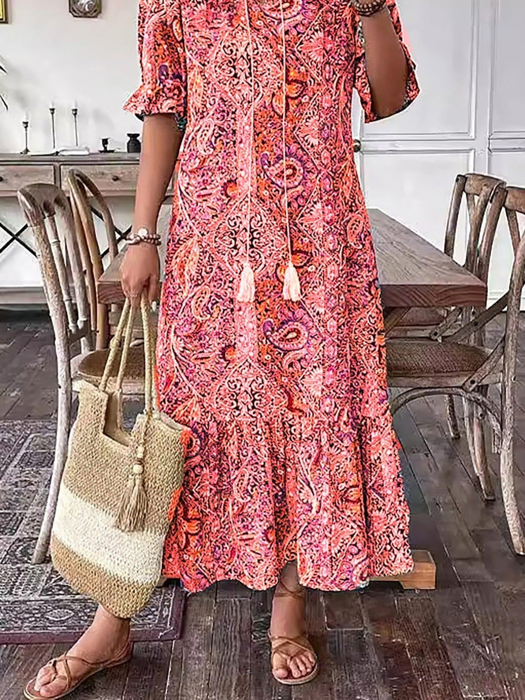 Boho grace dress in orange-red paisley print, close view of tassel neckline and tiered hem