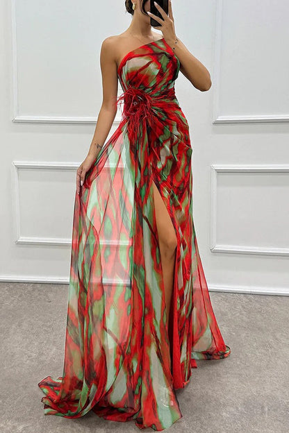 Red strapless maxi dress with abstract multicolor print, feathered waist detail, and slit