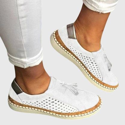 White orthopedic slip-on shoes with tassel detail and perforated upper, cushioned outsole
