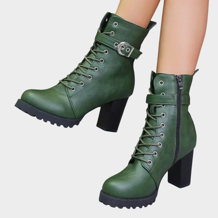Green flared heel ankle boots with lace-up front, buckle strap, and chunky tread sole