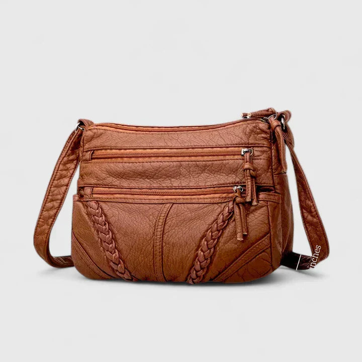Women’s brown leather crossbody bag, front view with braided detail and zip closure.