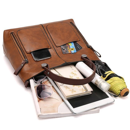 Brown PU leather crossbody tote with front zip pockets and top handle, shown with contents.