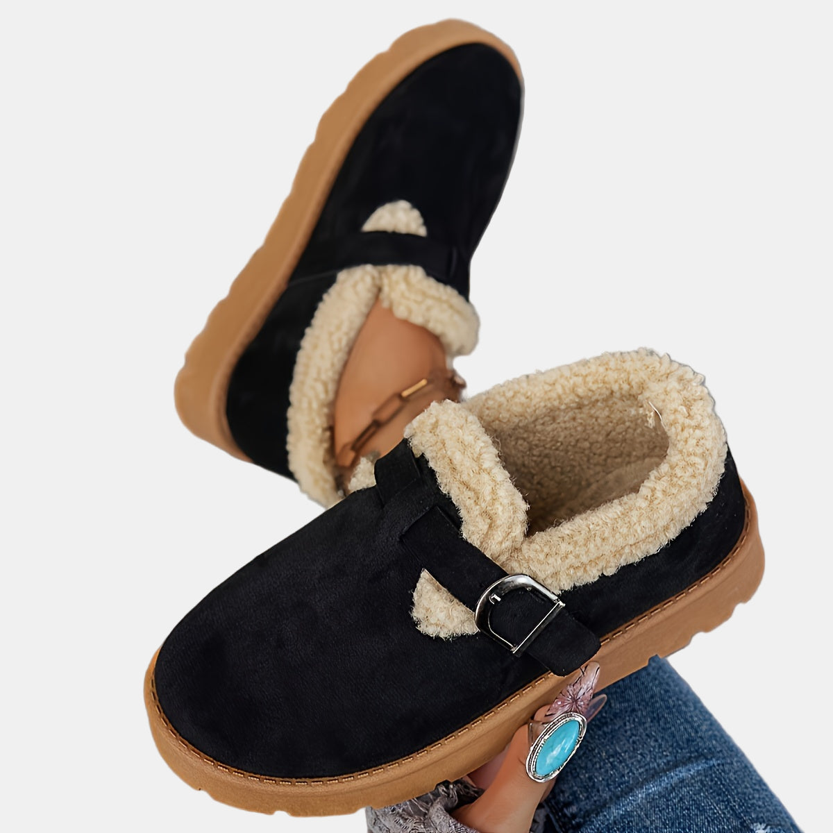 Black fleece-lined ankle boots with front strap buckle and tan-brown outsole