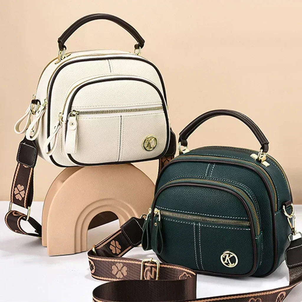 Cream and dark green mini crossbody shoulder bag with front zip pockets and logo emblem
