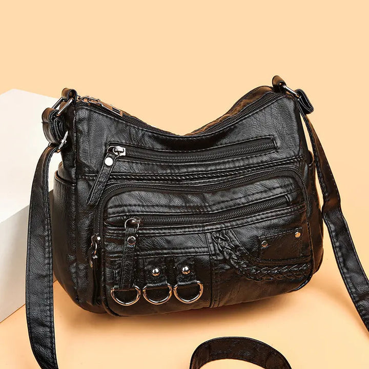 Black multi-layer crossbody bag with quilted texture, zippers, and front pocket hardware