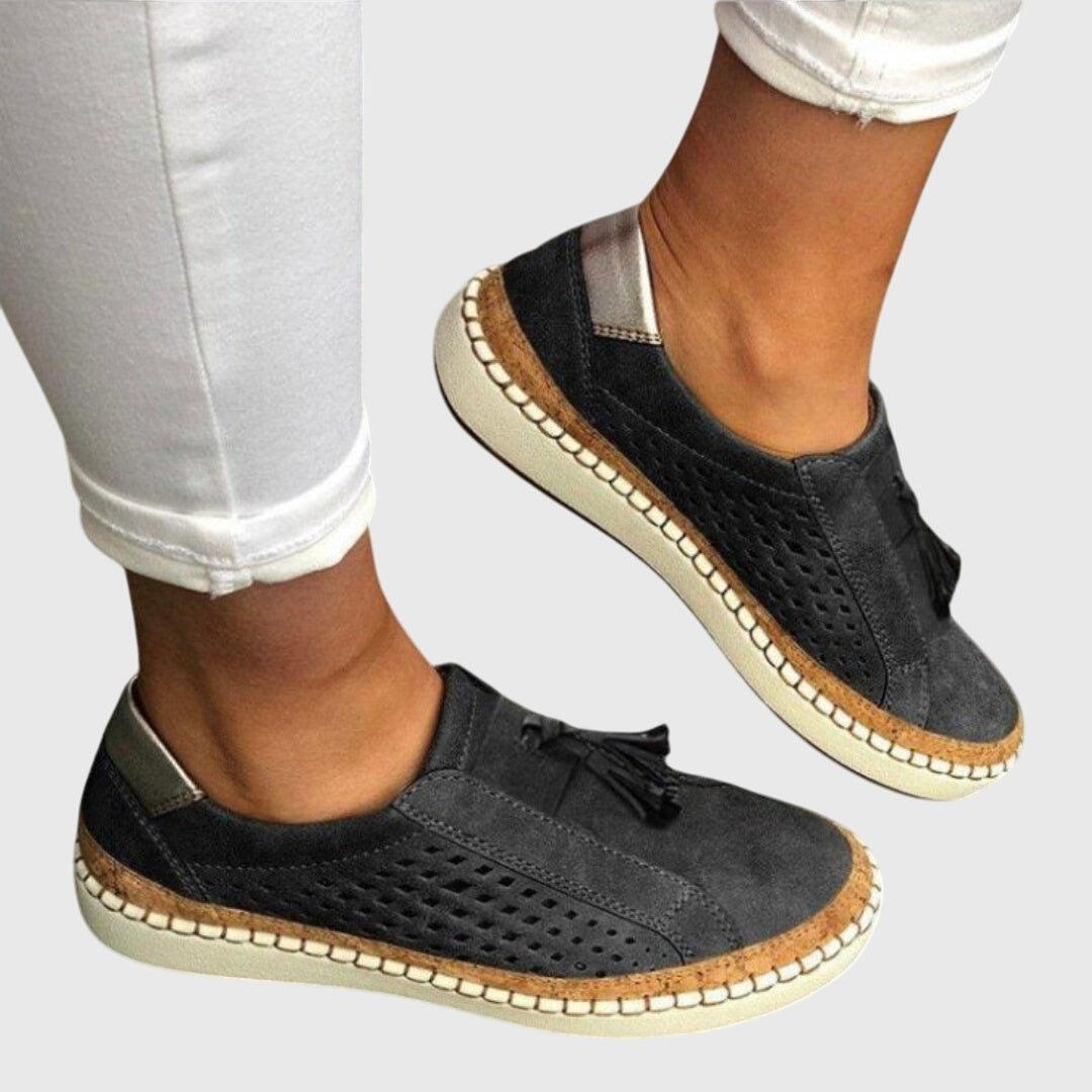 Black orthopedic slip-on shoes with tassel detail and perforated upper, cushioned outsole