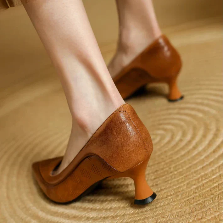 Brown pumps from the back with low heel and perforated leather look.