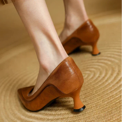Brown pumps from the back with low heel and perforated leather look.