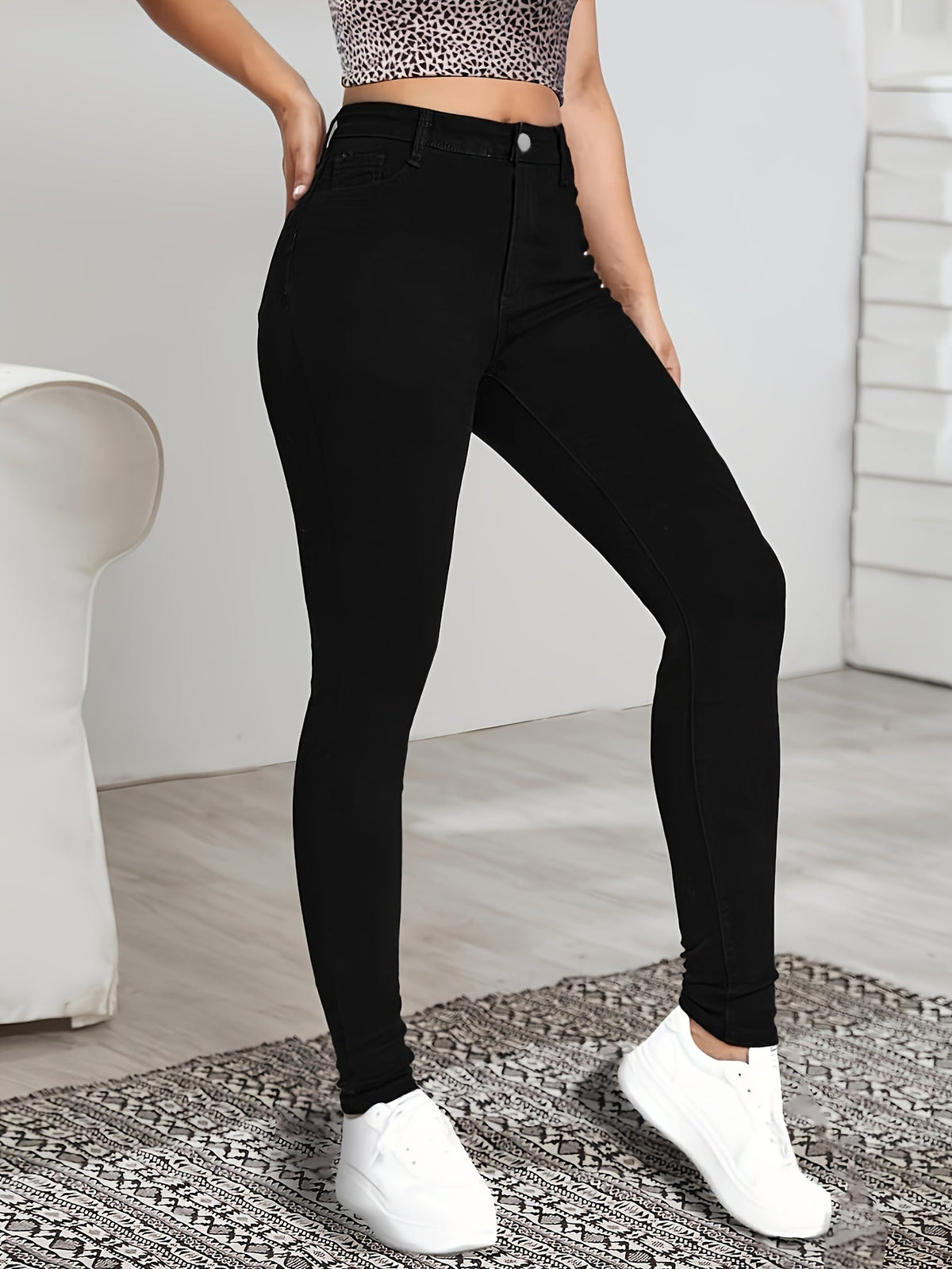 Black high-waist skinny jeans angled side view with seam detail and slim cuffs