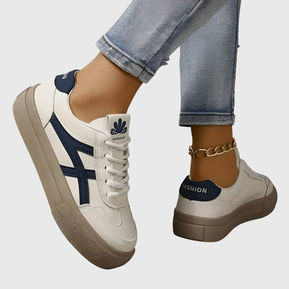 White orthopedic sneakers with navy stripes and thick tan sole, side and heel view