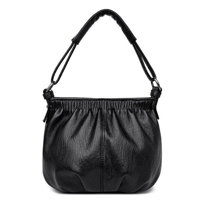 Black multi-layer handbag with gathered front, top handles, and central zipper pocket