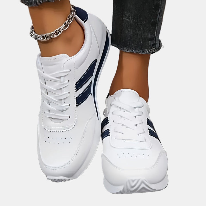 White orthopedic sneakers close-up with navy stripes and stitched leather panels