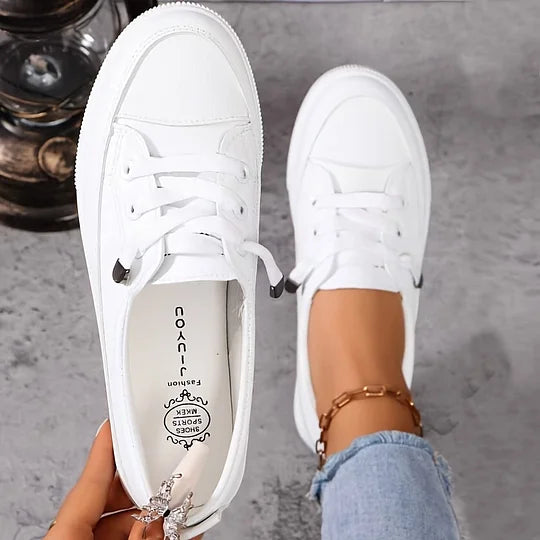 White low-top lace-up sneakers, rounded toe, visible laces and rubber tread sole