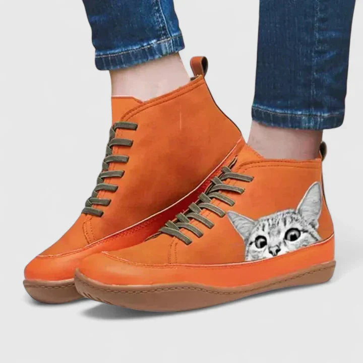 Orange lace-up orthopedic boots with gray cat face patch and cushioned sole, on feet